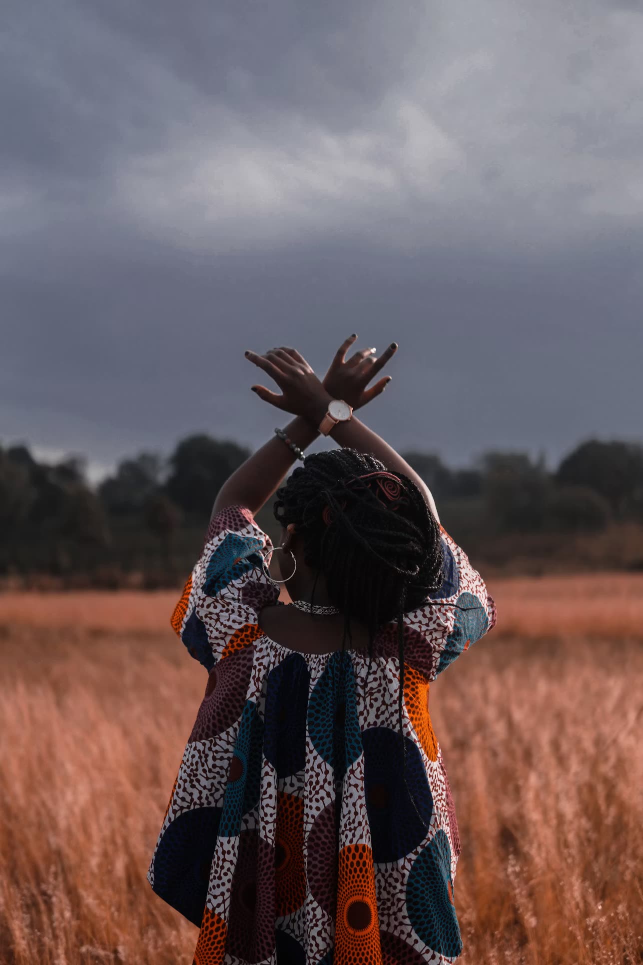 A woman standing in a wheat field at sunset.